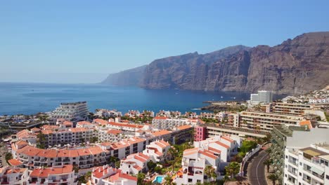 Coastal-mountains-along-Atlantic-Ocean-beautifully-captured-with-panning-drone-above-the-hotels-and-residential-buildings-of-famous-travel-destination-Santa-Cruz-of-Tenerife,-Canary-island,-Spain