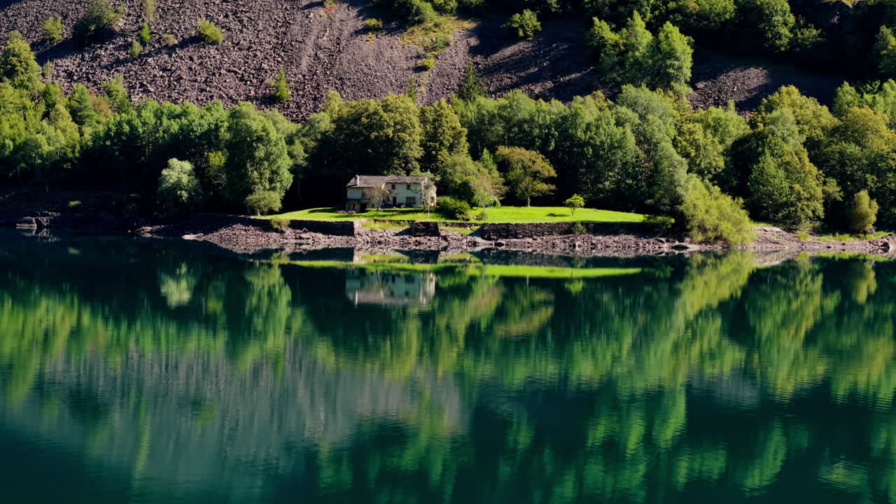 Lake house with forest reflection in serene Swiss landscape
