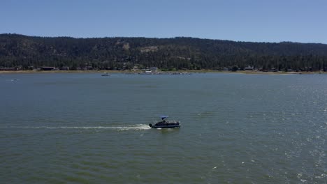 Aerial-drone-tracking-shot-of-a-blue-boat-in-Big-Bear-Lake-in-San-Bernardino-County,-California