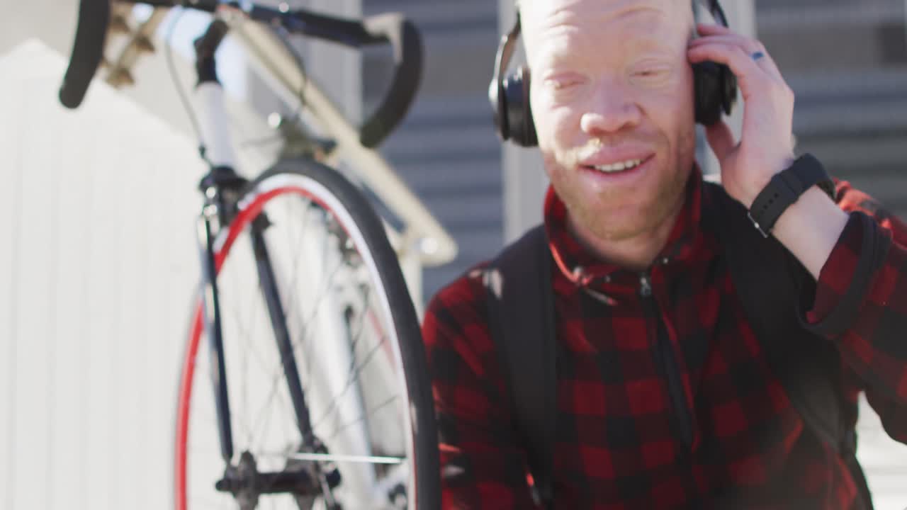 스마트 폰을 사용하는 헤드폰을 착용한 행복한 알비노 아프리카계 미국인