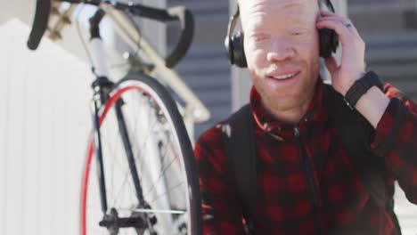 happy albino african american man with dreadlocks wearing headphones using smartphone