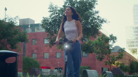 happy woman ride scooter on summer walk. stylish asian lady drive city street.