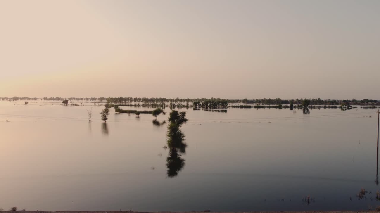 antena ascendente desde la carretera para revelar tierras de cultivo inundadas en sindh durante la puesta de sol