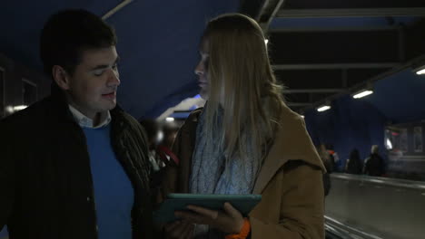 Young-couple-with-pad-riding-on-flat-escalator