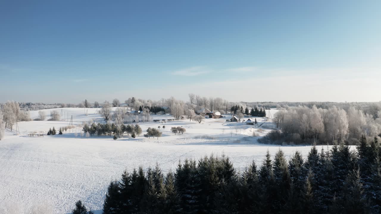Scenic aerial drone view of a cozy country house in a sunny snow-covered winter morning. Lifestyle of living in countryside. Clean environment.