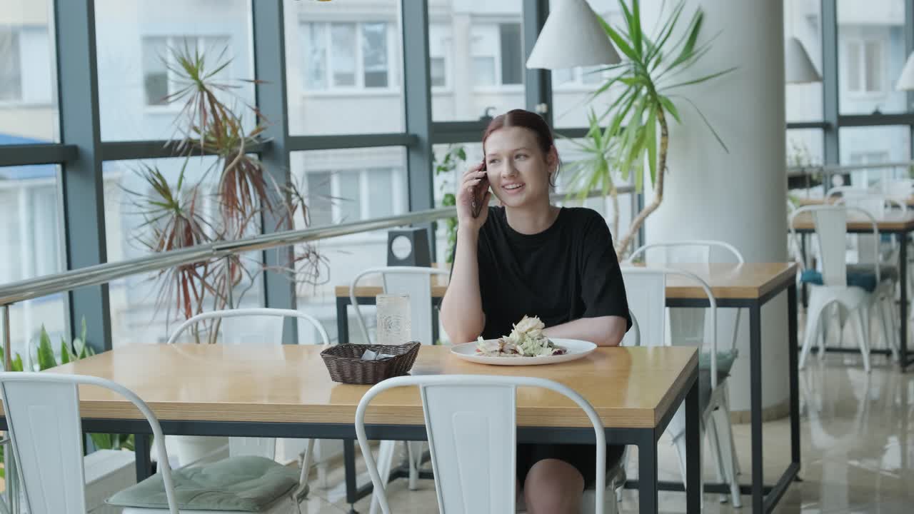 점심을 먹는 동안 현대적인 레스토랑에서 전화로 이야기하는 여자