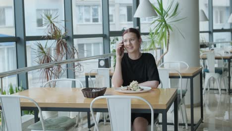 mujer hablando por teléfono en un restaurante moderno mientras almuerza