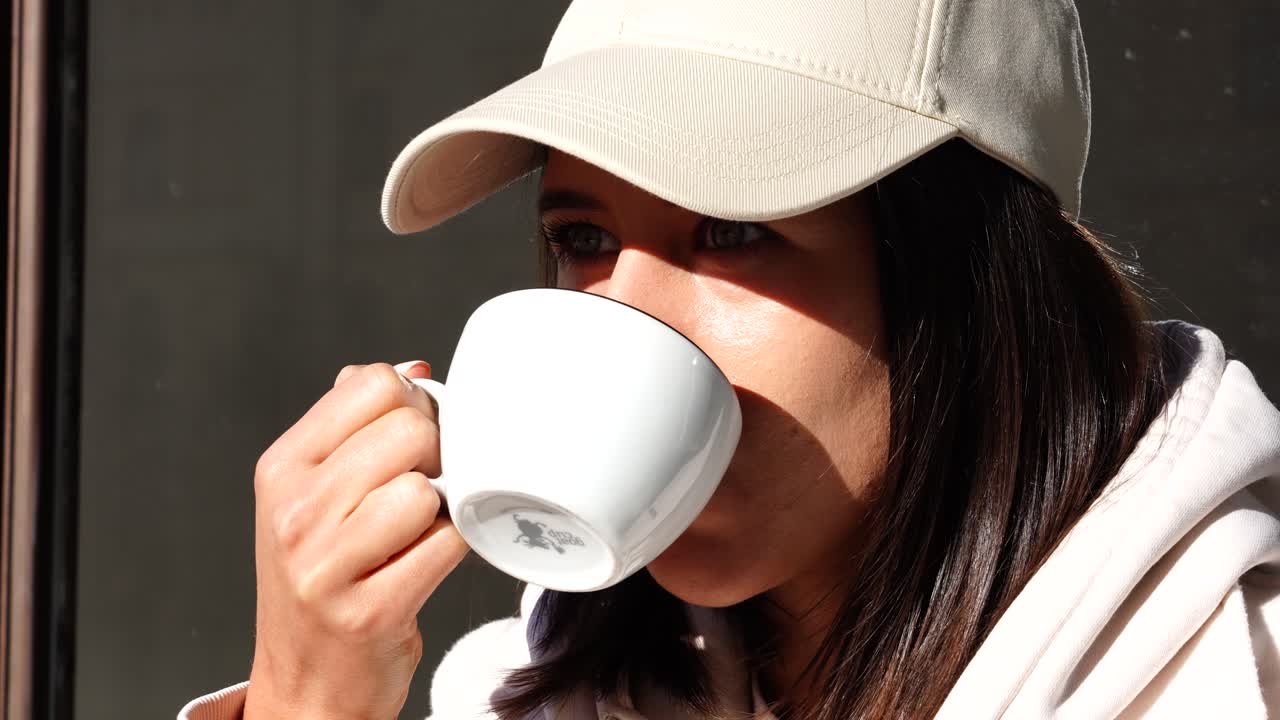 mujer beber y disfrutar de una taza de café durante un brillante día soleado en una cafetería al aire libre