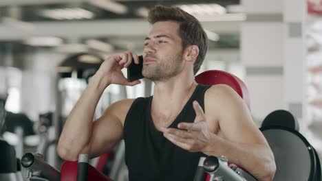 handsome man talking mobile in fitness club. closeup sportsman having break