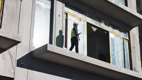 construction worker inspecting a balcony on a high-rise building under construction