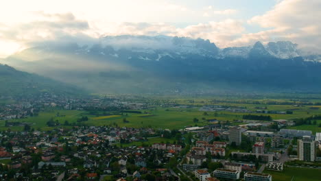 Panoramic-View-Of-Tranquil-Townscape-With-Snowcapped-Mountains-At-Background-In-Switzerland