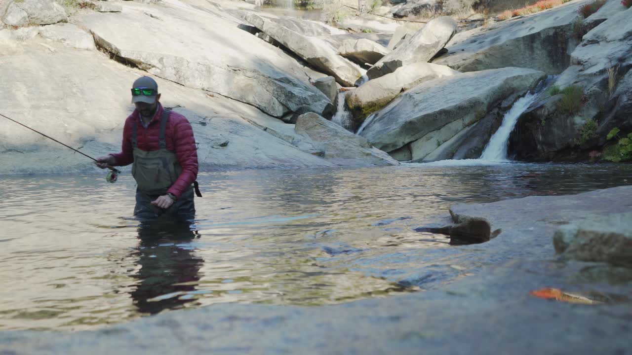 toma estática de un hombre caucásico que sale del río después de pescar con mosca