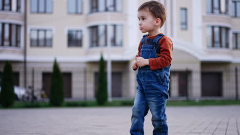 happy active caucasian toddler turning around outdoors. baby boy having fun during his walk. blurred backdrop.