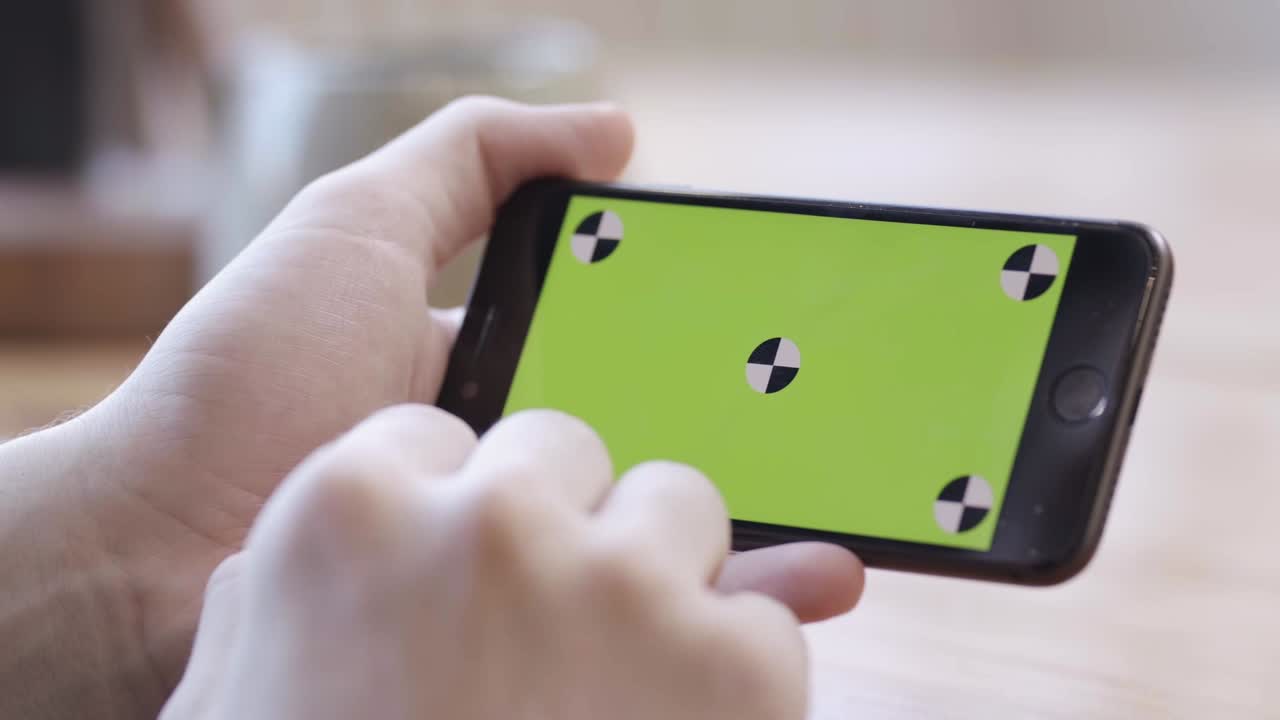 초록색 화면 을 가진 스마트폰 을 들고 있는 사람