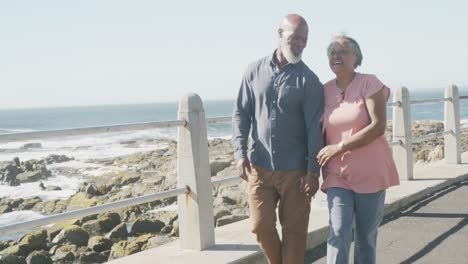 feliz pareja afroamericana mayor caminando por el paseo marítimo junto al mar, cámara lenta