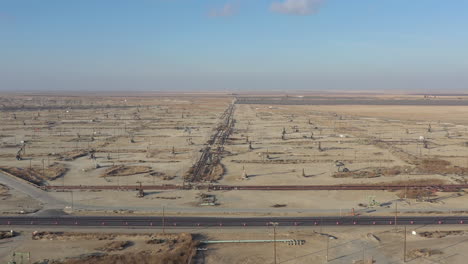 drone flying backwards over wells with pump jacks on oil field, california usa
