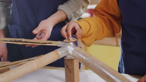 primer plano de un equipo multicultural en un taller de ensamblaje de un marco de bicicleta de bambú sostenible construido a mano