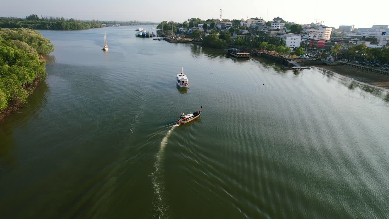 drone aéreo de un barco tailandés de cola larga en el río llegando a la ciudad de krabi tailandia durante el verano al atardecer