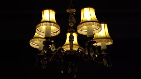 old british chandelier light in the dark hanging in a home with slow push in