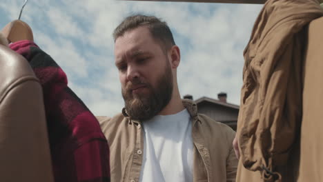 man looking at second hand jackets at garage sale