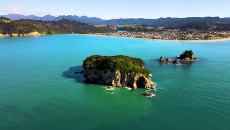 Beautiful-aerial-orbit-reveal-of-tropical-islands,-forested-hills,-beach-and-Whangamata-town,-New-Zealand-seascape
