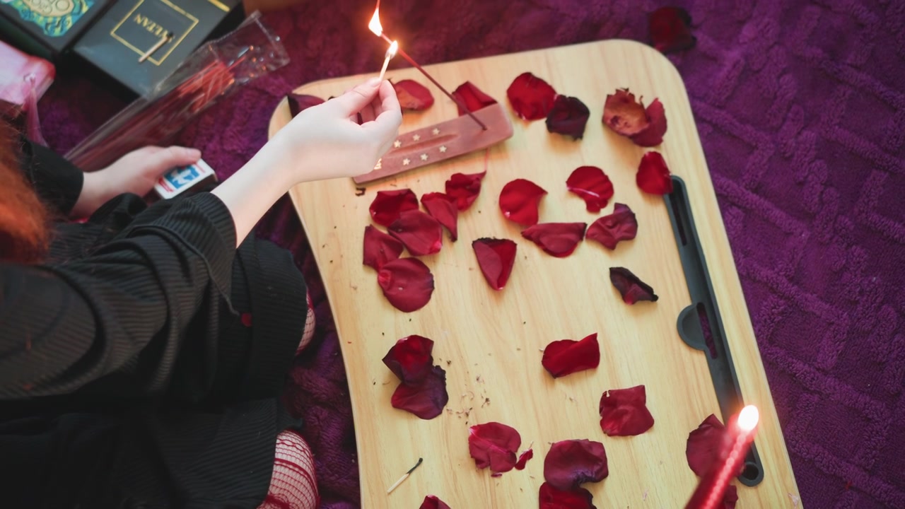 Overhead tray with rose petals, hands arranging spread for tarot reading, candle flame flicker and tarot book nearby, reader preparing ritual for fortune and foresight, cozy purple bohemian mood
