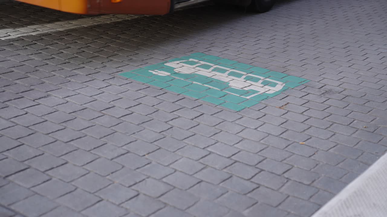 autobús eléctrico que sale de la central eléctrica después de recargar la batería, pasando el cartel del logotipo de carga en el suelo.