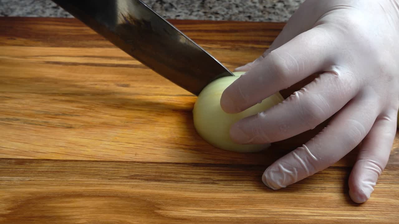Chef's hands with knife cutting the onion on the wooden board. Preparation for cooking. Healthy eating and lifestyle