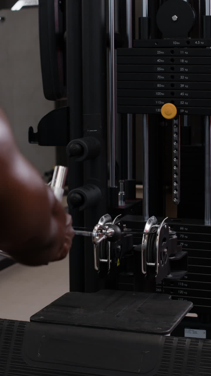 체육관 에서 앉아있는 케이블 줄 운동 을 하는 사람