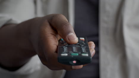 persona que sostiene un control remoto de la televisión