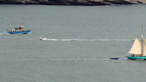 Tourist-boat,-sailboat-and-speedboat-passing-through-frame-at-Falmouth