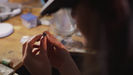 Close-up-of-hands-of-caucasian-female-jeweller-wearing-glasses,-checking-jewelry-at-workshop