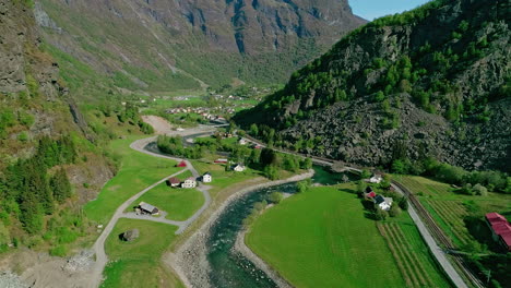 Beautiful-village-near-mountain-river-in-massive-valley-in-Norway,-aerial-view