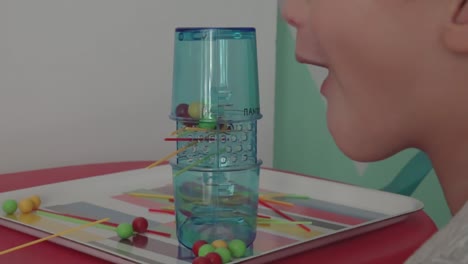 niño caucásico de cuatro años jugando al juego clásico kerplung en casa, vista lateral trasera 120fps