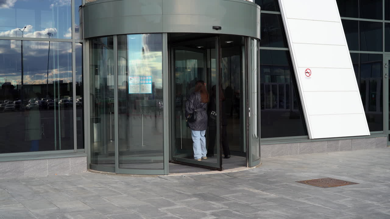 Modern Building Entrance with Revolving Doors and People