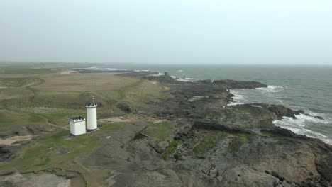 An-aerial-view-of-Elie-Ness-lighthouse-and-surrounding-coastline-on-a-misty-day,-Fife,-Scotland