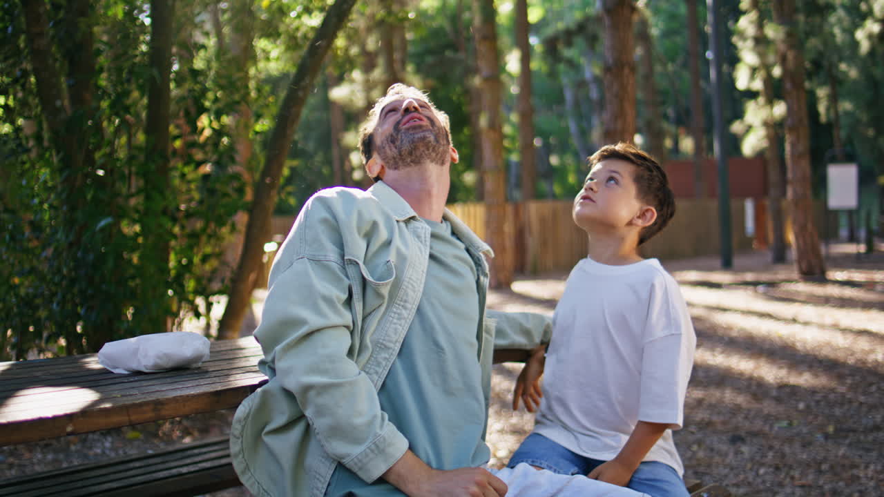 Interested family looking up sitting bench at sun beams park weekend closeup