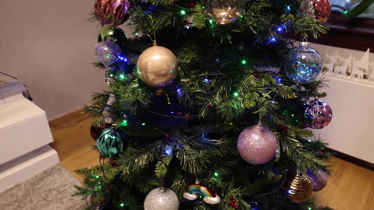 Primer plano de una mujer decorando un árbol de Navidad en su sala de estar.