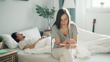 woman looking at pregnancy test in bedroom