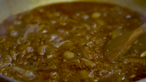 espátula de madera revolviendo la salsa de curry a fuego lento con cebollas