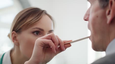 handheld view of doctor checking throat of senior man