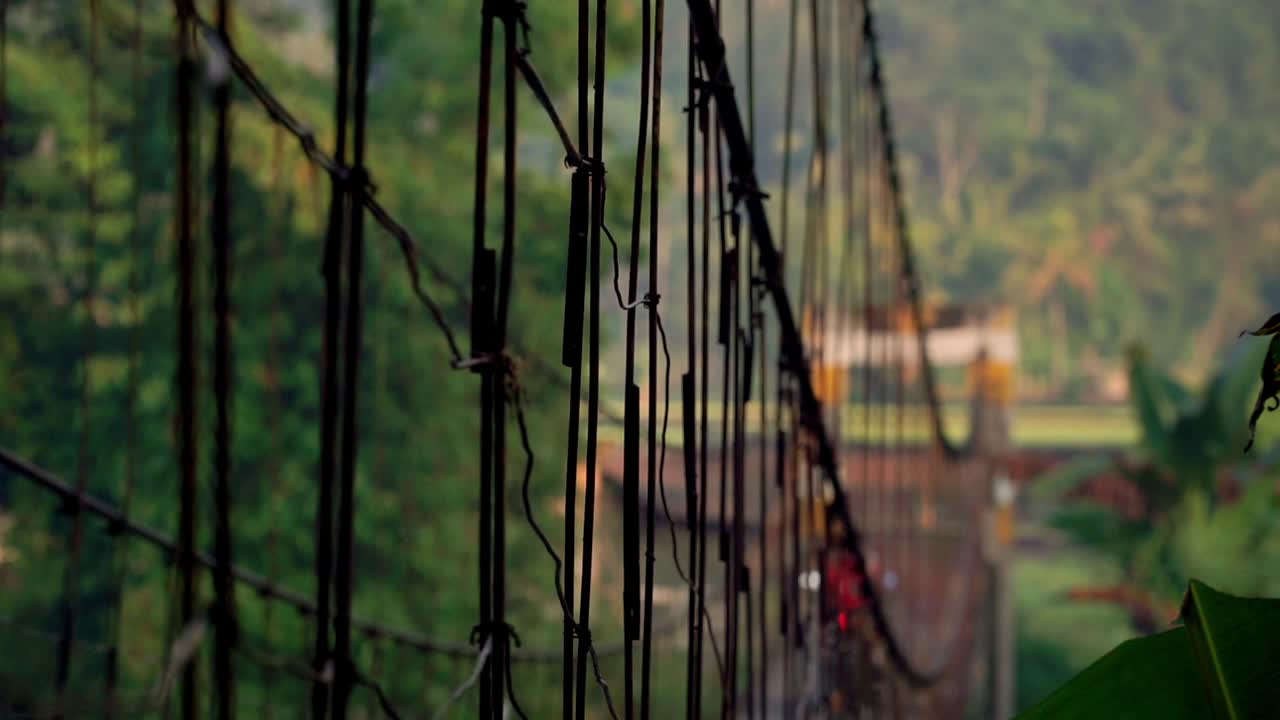 People without helmet driving on suspension bridge in tropical village of Indoensia