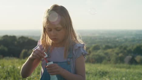 cute caucasian girl playing with bubbles at the meadow.