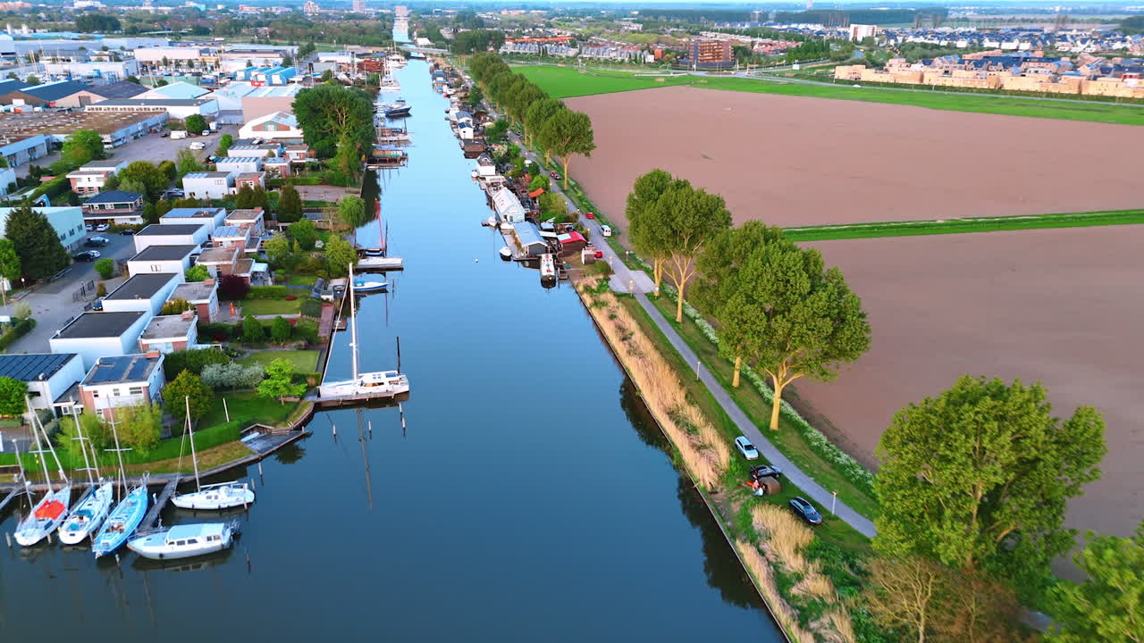 Daytime canal view, Netherlands. Peaceful waterway lined with boats and greenery in the Netherlands showcases rural charm in a bright daylight setting