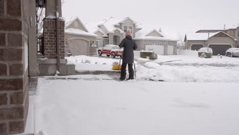 senior woman clears the walkway of snow