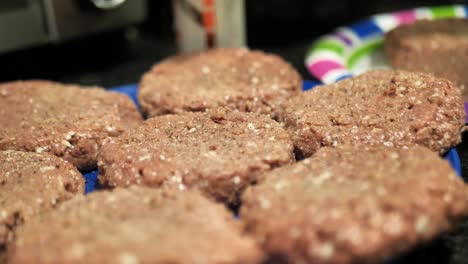 Seasoning-plant-based-burger-patties-on-a-blue-plate-for-a-summertime-barbecue-cookout,-close-up-shot-in-60-frames-per-second-4k