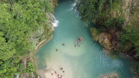 bird's-eye view, canyoneering tourists arriving kawasan falls swimming in emerald blue water, cebu