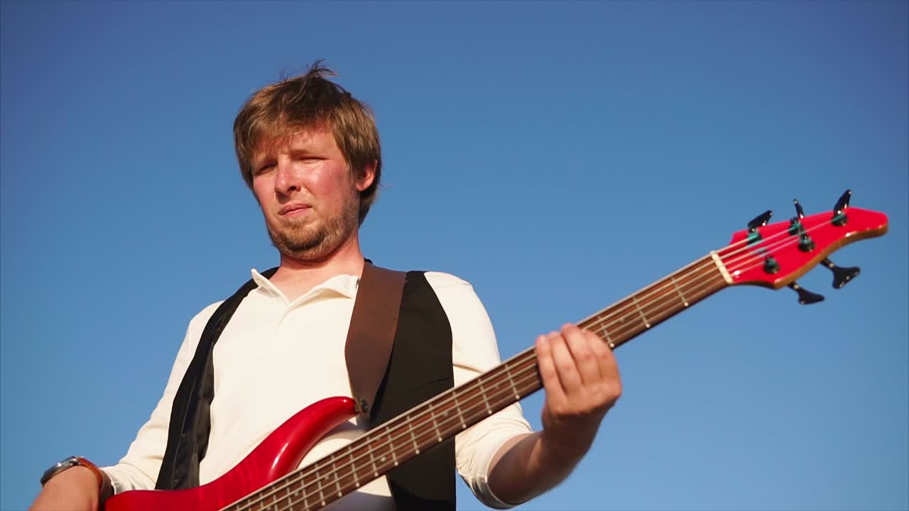 Man Playing Red Bass Guitar Outdoors