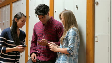 estudiantes en sus teléfonos inteligentes apoyados en armarios