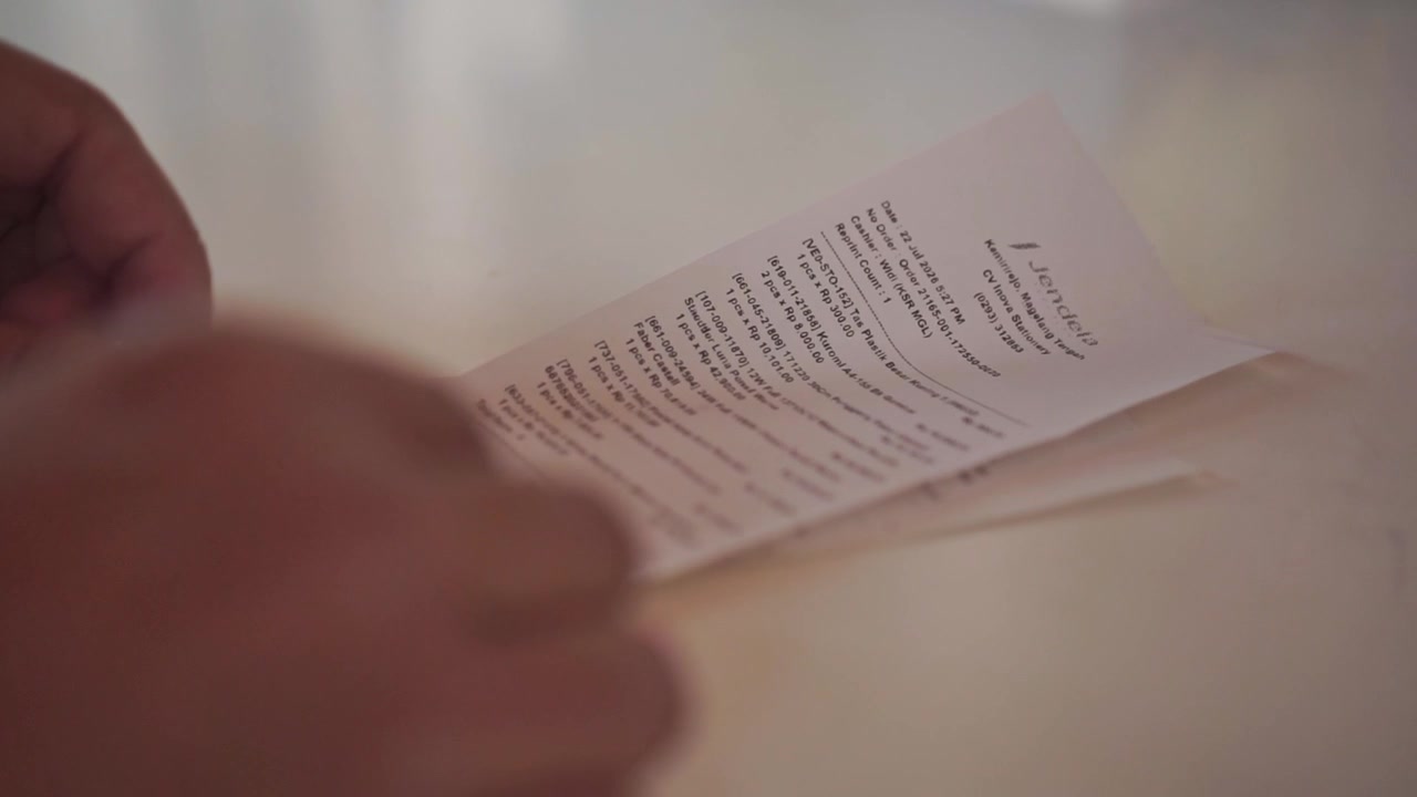 hand placing paper receipt on to the table, reading transaction details, financial record and shopping expense concept.